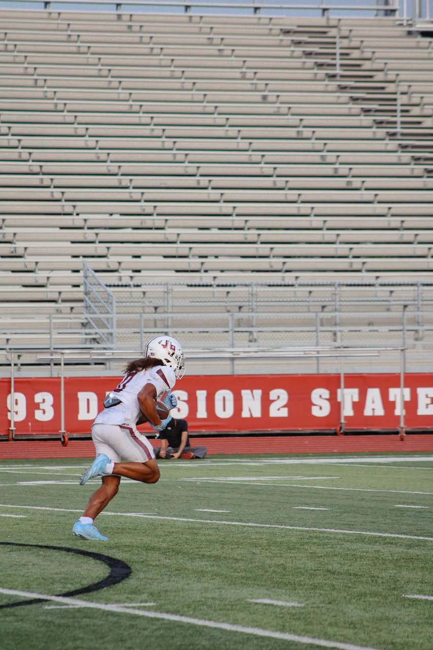 Football player in white accelerating through open field